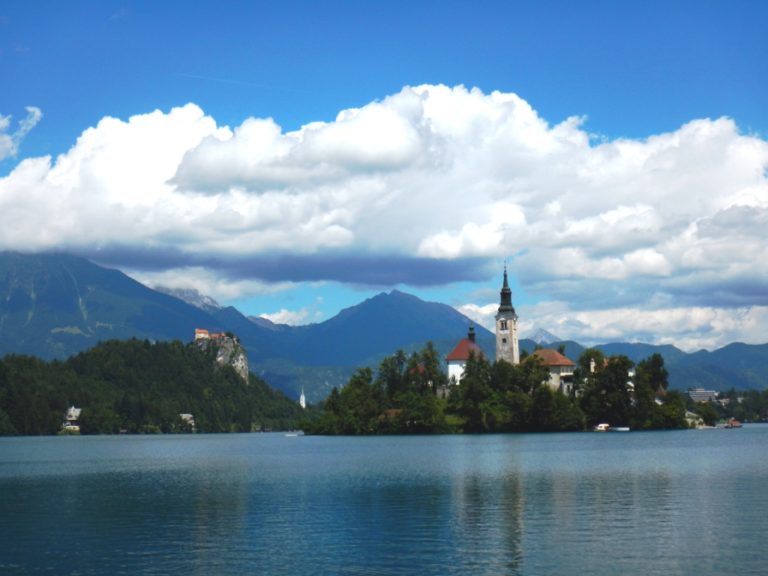 Typická scenérie jezera Bled. V levé části snímku bledský hrad, v popředí jezerní ostrov s kostelem.
