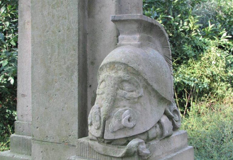 Památník obsahuje i stylizovanou přilbu, ve které poznáme část zbroje hoplíty, starořeckého pěšího bojovníka.