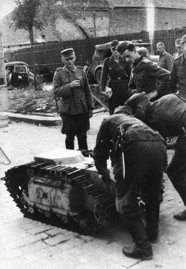 Němečtí vojáci manipulují s dálkově ovládaným „minitankem“, pásovým nosičem náloží Goliath. Zdroj foto:  Bundesarchiv, Bild 101I-695-0412-19 / Götze / CC-BY-SA 3.0, CC BY-SA 3.0 DE , via Wikimedia Commons