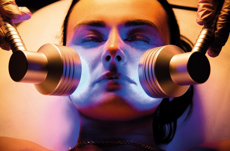 Led Light Therapy.Chromotherapy procedure with Hydrafacial device.Woman doing LED face therapy in blue