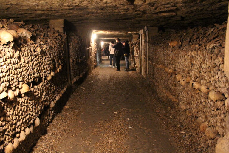 Turisté kráčejí chodbou, obklopeni kostmi a lebkami na stěnách...